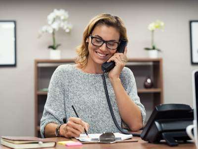 A woman on the phone in an office speaking to a client